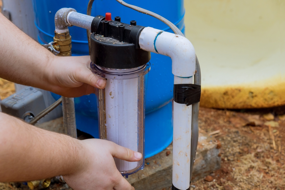 A closeup of someone adjusting a water filter on a pipe.