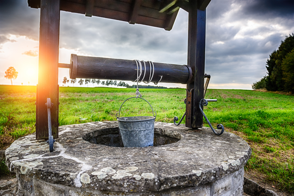 A well with the sun setting in the background.