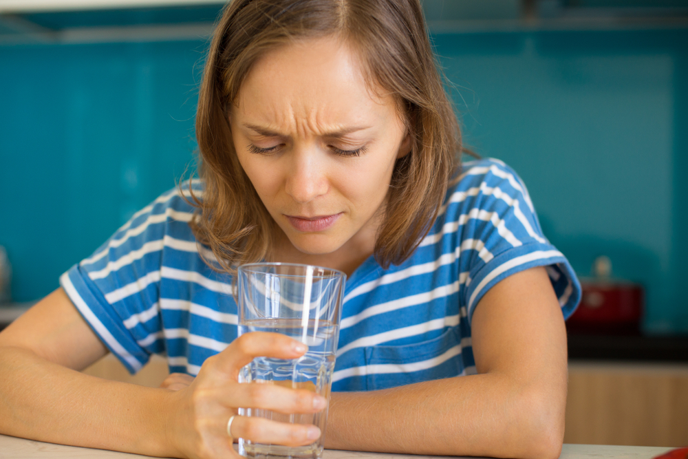 A woman looking into her glass of water.