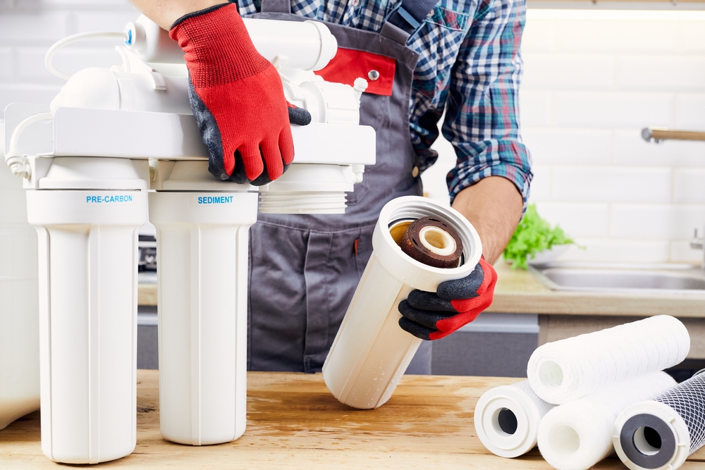 A person in their kitchen disassembling a water filter to clean it.